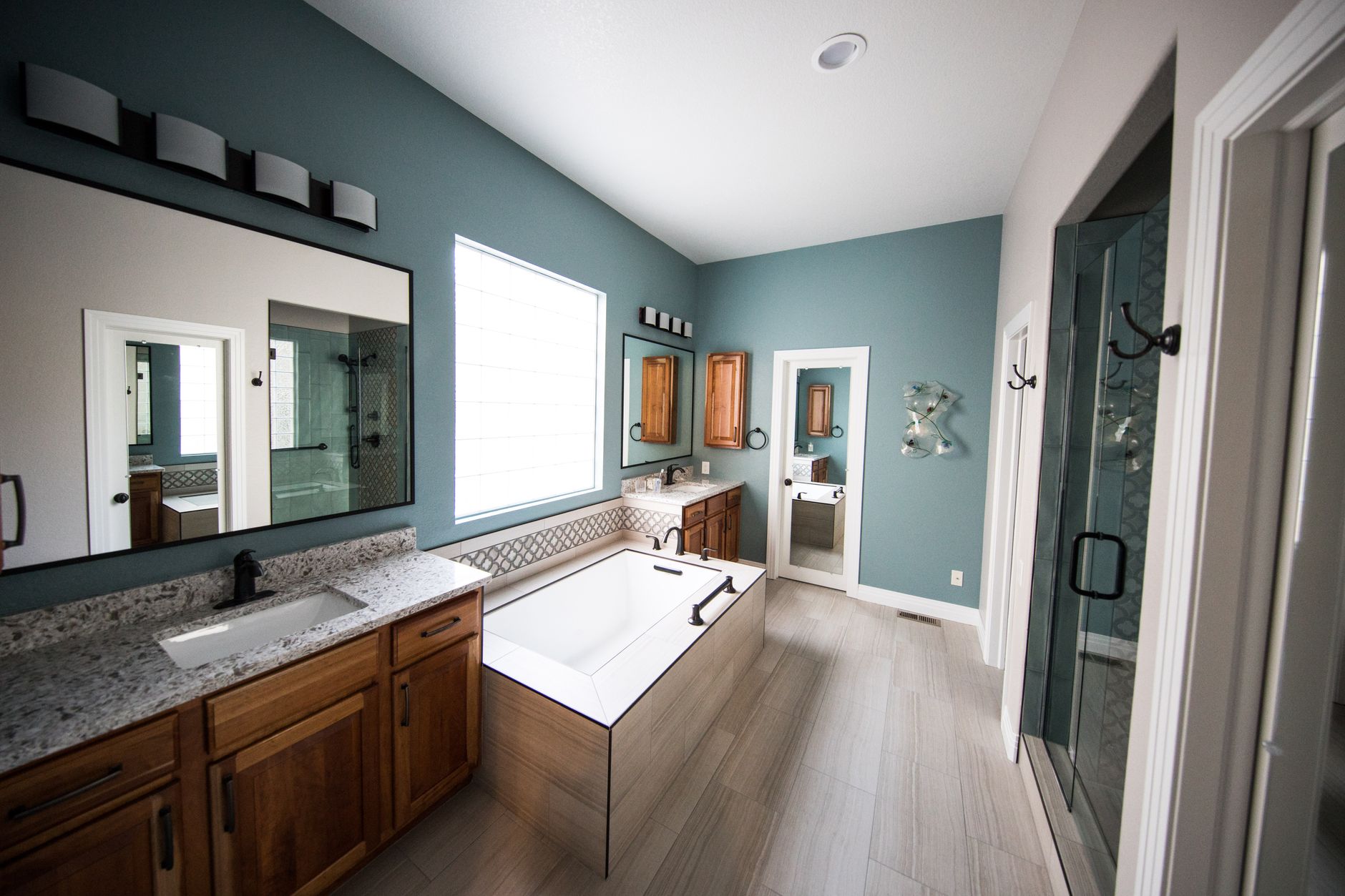 A spacious modern bathroom featuring a freestanding bathtub, wooden cabinets, and granite countertops for bathroom remodeling Waterloo IL guidance