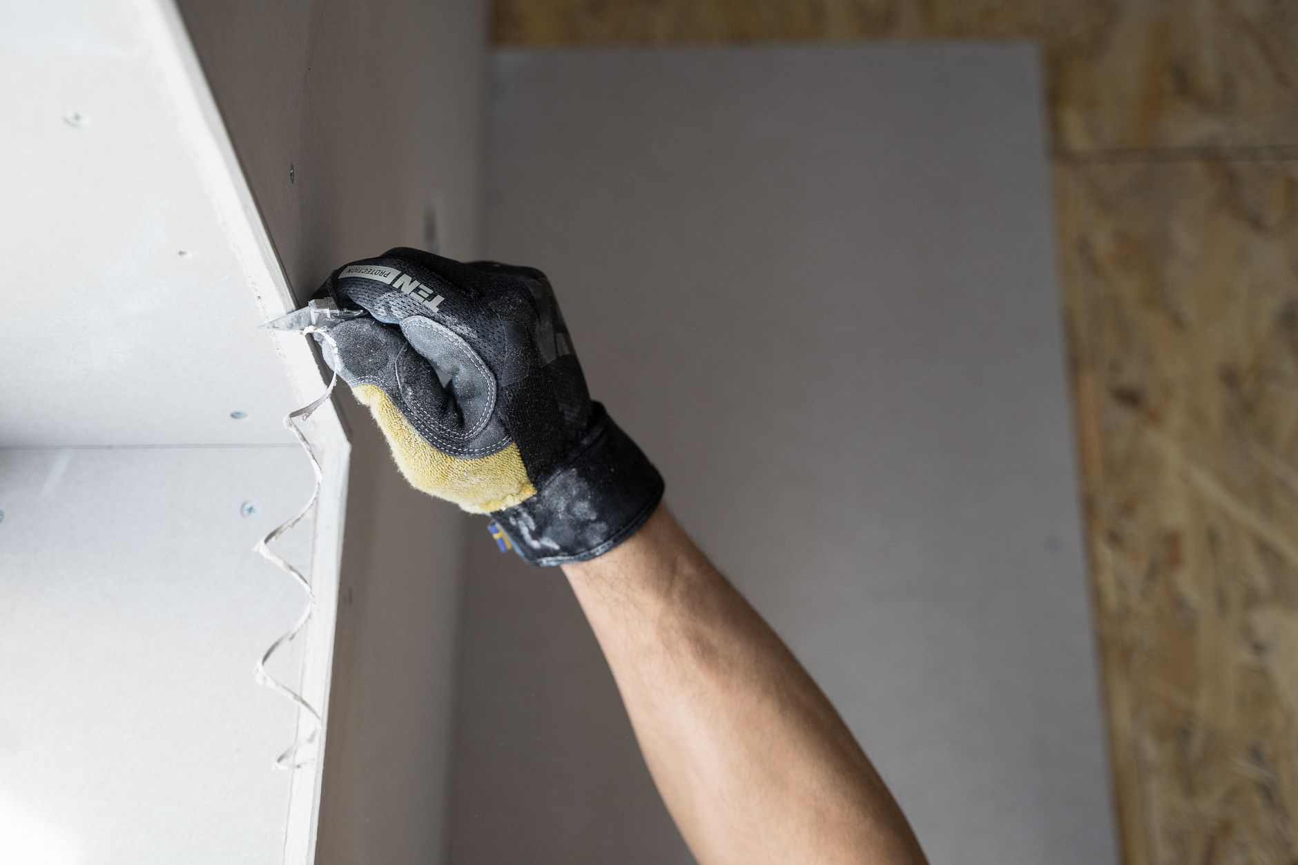 Close-up of a gloved hand applying plaster to a wall indoors in Falun, Sweden for drywall repair Columbia IL guidance