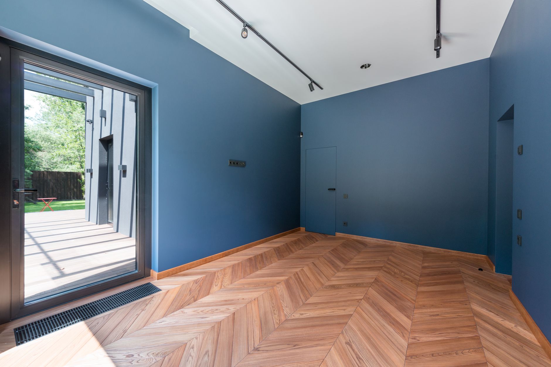 Contemporary interior room with blue walls, wooden flooring, and large glass door for flooring installation Swansea IL guidance