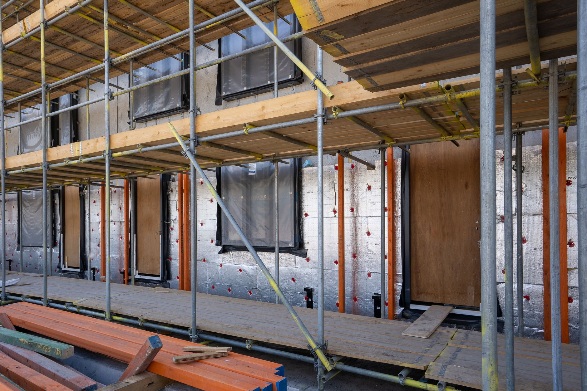Reflective exterior home insulation installed behind scaffolding during residential construction