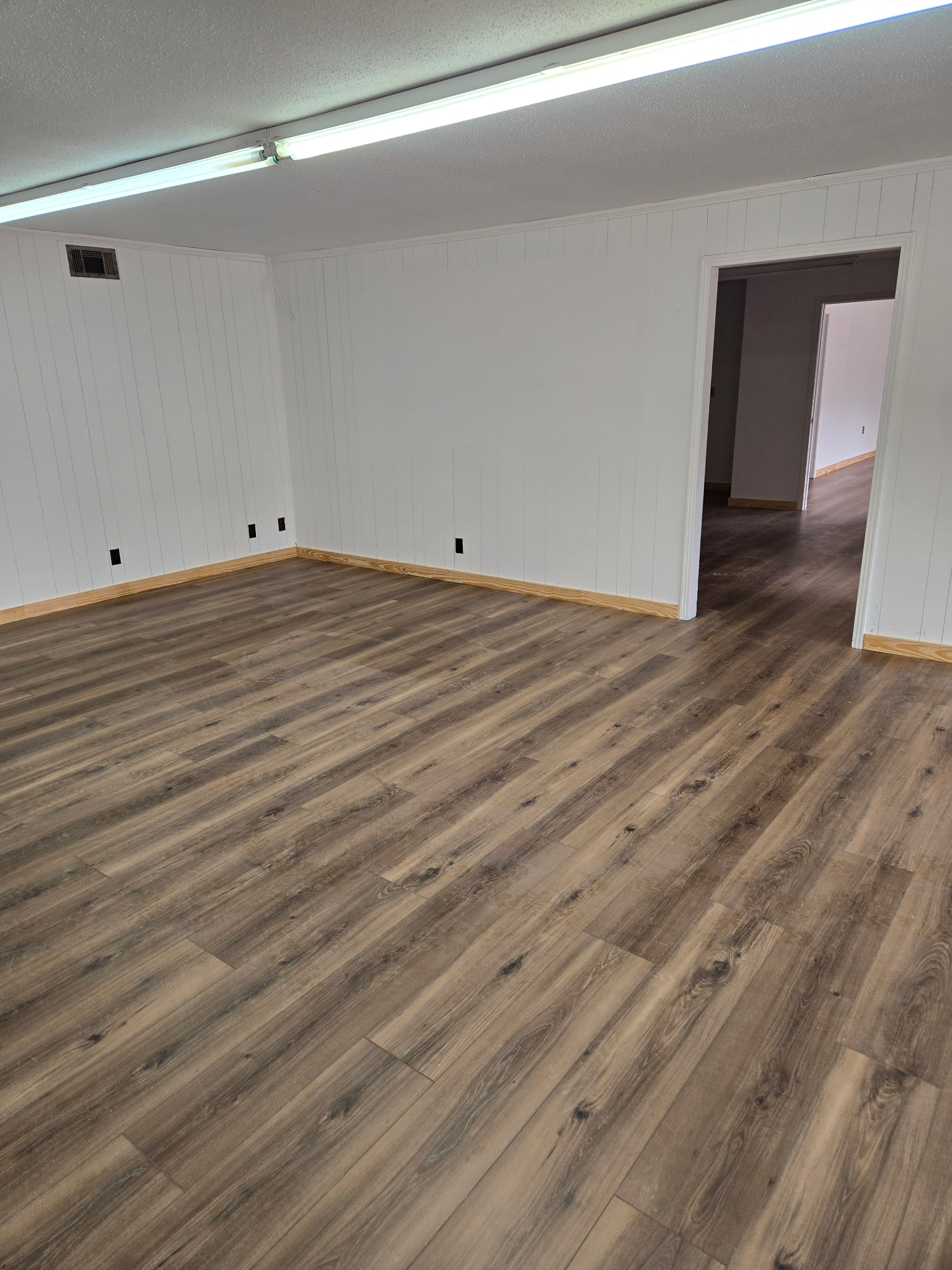 Finished interior room with wood-look flooring and new trim after wall and drywall work