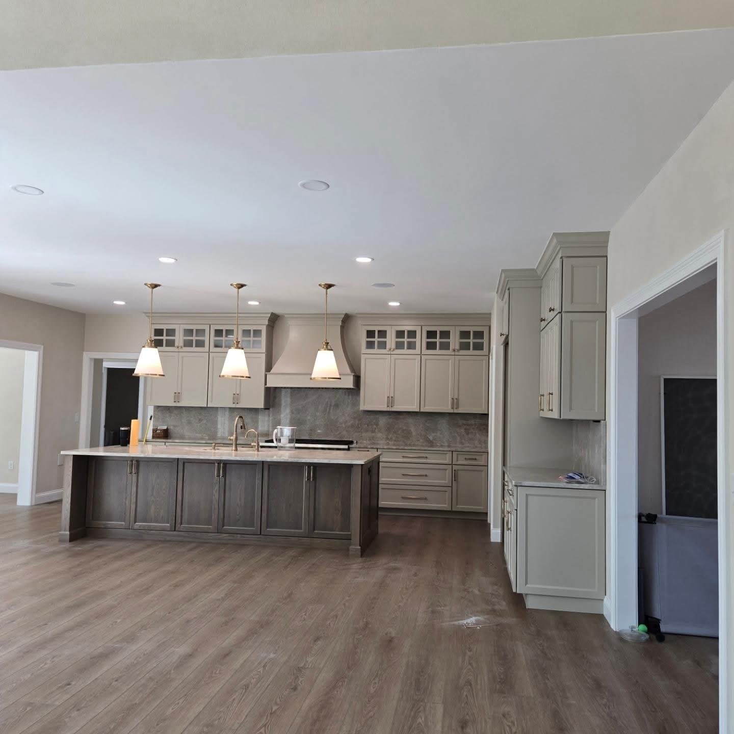 Finished smooth kitchen ceiling above the island, with recessed lights and three pendant lights.