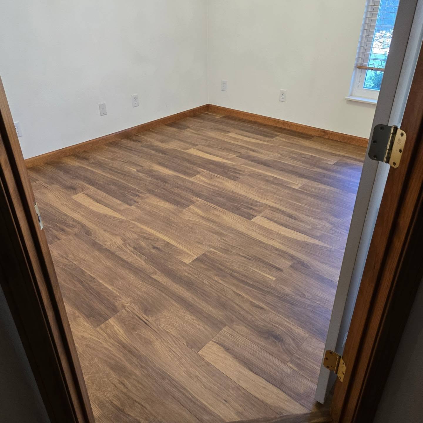 Completed Valmeyer bedroom with wood-tone LVP flooring and matching trim