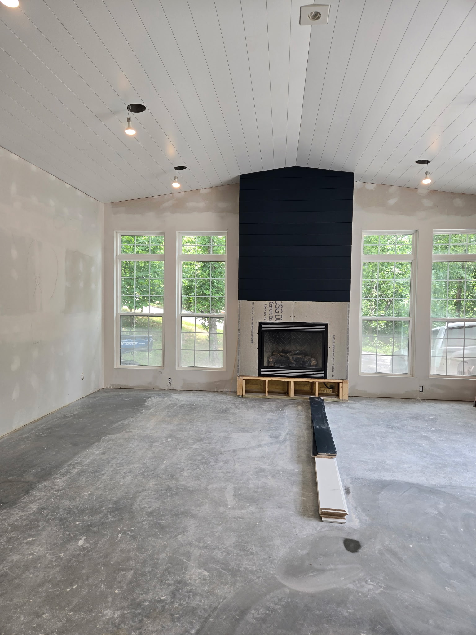 Finished white shiplap ceiling and black shiplap fireplace surround with drywall finishing in progress